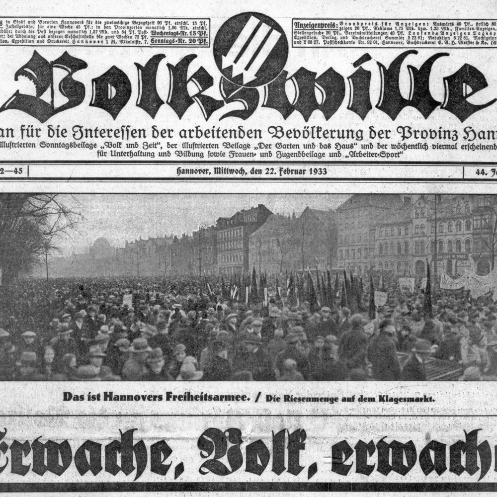 Hannover: Titelseite der sozialdemokratischen Zeitung "Volkswille" vom 22.02.1933, Auszug. Mit dem Emblem der Eisernen Front und einem Foto der Kundgebung am 19. Februar 1933: „Das ist Hannovers Freiheitsarmee / Die Riesenmenge auf dem Klagesmarkt“. Bildarchiv des Historischen Museum Hannover