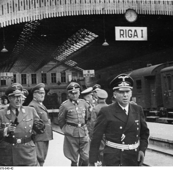 Herrenmenschen im Ostland: Ankunft deutscher Offiziere am Bahnhof Riga, 15. Februar 1944. Darunter SA-Obergruppenführer und Reichskommissar Ostland Hinrich Lohse (3. v.l.) sowie General der Polizei und SS-Obergruppenführer Friedrich Jeckeln (5. v. l.). Bundesarchiv Bild 146-1970-043-42. Wikimedia Commons