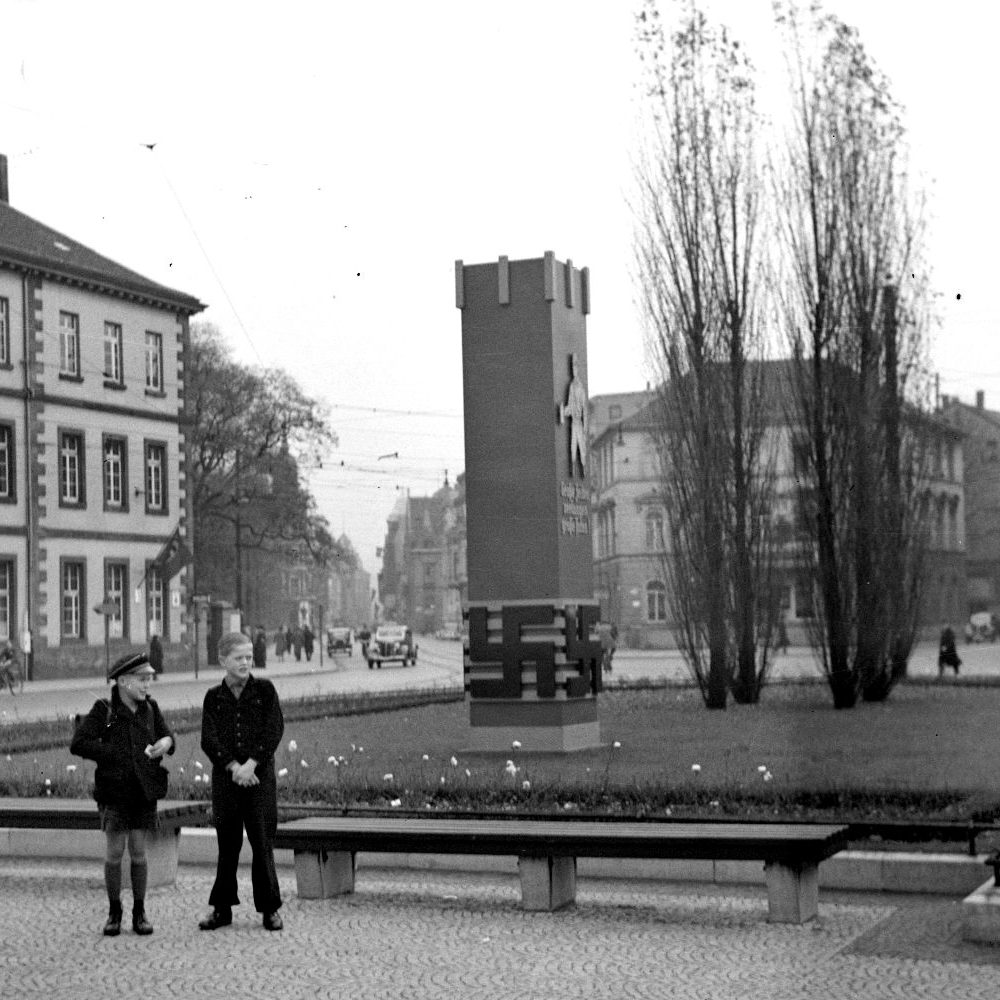 Hannover: Horst-Wessel-Platz (vor 1933 und nach 1945: Königsworther Platz) mit NS-Propagandastele, o. J. (1930er/1940er Jahre). Geradeaus geht der Blick in die Straße der SA (vor 1933 und nach 1945: Lange Laube), rechts angeschnitten die Villa Simon an der Brühlstraße. (Bildarchiv Historisches Museum Hannover
